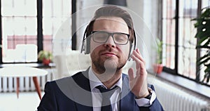 Happy calm professional businessman listening to music in office, closeup