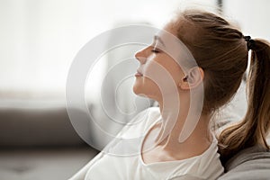 Happy calm woman relaxing breathing fresh air dreaming on couch