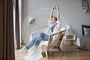 Happy calm young woman relaxing closed her eyes on cozy chair in living room