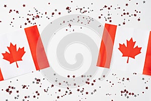 Happy Canada Day greeting card design. Canadian flags with maple leaves and confetti on white background. Flat lay, top view