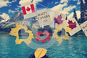 Happy Canada Day. Holiday greeting cards and color maple leaves hanging on rope in Canadian Rockies