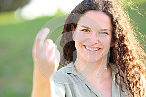 Happy candid woman saying come here in a park