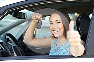 Happy car owner with a key and thumbs up photo