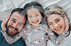 Happy carefree caucasian family in pyjamas from above lying cosy together in bed at home. Loving parents with their