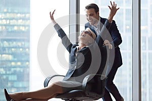 Happy carefree middle-aged businesswoman enjoying office activity riding on chair