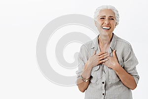 Happy carefree old woman satisfied with how life going. Joyful charming senior lady with grey hair in loose shirt