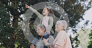 Happy, carefree and playful grandparents playing with their granddaughter outdoors in a nature park. Young girl having