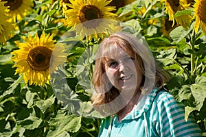 Happy, carefree senior woman 60-65 smiles in a field of sunflowers on a sunny day