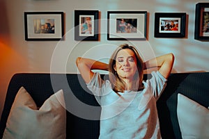 Happy Carefree Smiling Woman Sitting on a Sofa at Home Rexaxing elaxing