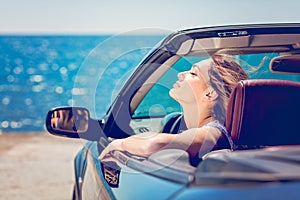 Happy and carefree woman in the car on the beach