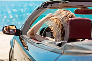 Happy and carefree woman in the car on the beach