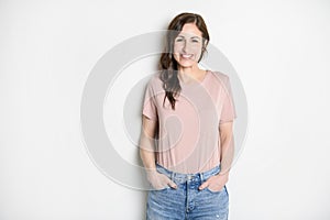 Happy carefree woman with joyful expression, smiling while standing in relaxed pose against white background
