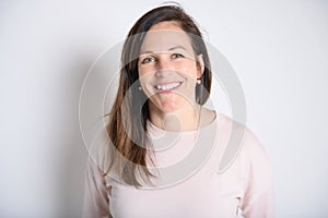 Happy carefree woman with joyful expression, smiling while standing in relaxed pose against white background