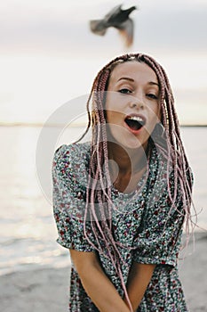 Happy carefree young woman with african braids in pink round sunglasses enjoy her life on the beach, summer vacation