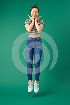 Happy carefree young woman jumping isolated over green background