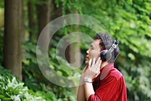 Happy careless free Asian Chinese man is listening to music and wearing a earphone