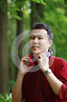 Happy careless free Asian Chinese man is listening to music and wearing a earphone