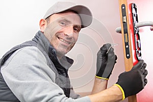 happy carpenter during process wood door hinge installation