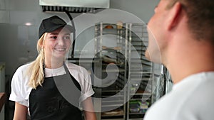 Happy cashier talking to the client in pastry store. Man came shop. Seller
