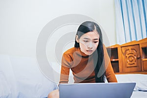 Happy casual asian woman working in bed with laptop in the house, WFH work from home concept