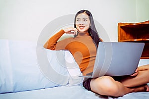 Happy casual asian woman working in bed with laptop in the house, WFH work from home concept photo