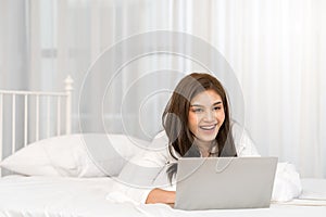 Happy casual beautiful asian woman working on laptop computer