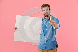 Happy casual man holding board and making thumbs up sign