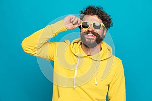 Happy casual man with moustache fixing sunglasses and smiling