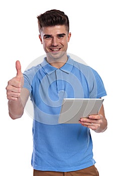 Happy casual man working on tablet makes ok sign