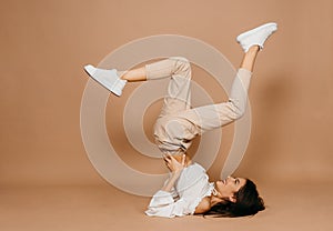 Happy casual woman lying on the floor with raised legs up over pastel background. Lady, cute.