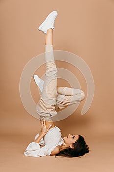 Happy casual woman lying on the floor with raised legs up over pastel background. Lady, cute.