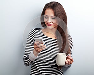 Happy casual woman texting sms and holding in hand cup of coffee