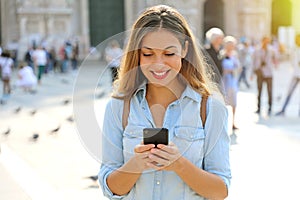 Happy casual woman wearing shirt texting on the smart phone walk