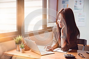 Happy casual young businesswoman working on a laptop computer in office at her home. Working at home concept