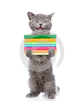 Happy cat standing on hind legs and holding a stack of books. isolated on white background