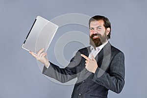 Happy caucasian bearded hipster with computer. male employee holding finance report and researches in coworking space on