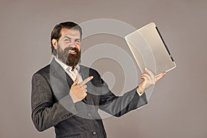 happy caucasian bearded hipster with computer. male employee holding finance report and researches in coworking space on