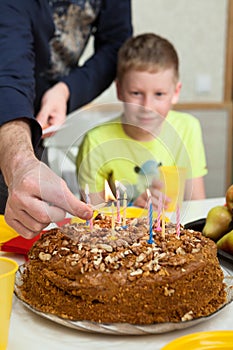 Happy Caucasian boy celebrating his birthday and ready to blow candles on homemade baked cake