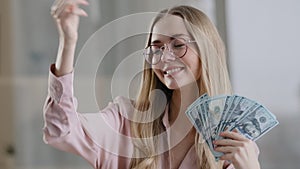 Happy caucasian business woman in glasses rich successful girl winner female throws money in air rejoices with banknotes