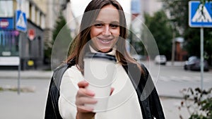 Happy caucasian business woman in a white sweater and black leather jacket walks down the street to her company office