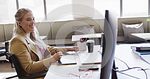 Happy caucasian casual businesswoman in wheelchair using tablet in office, in slow motion