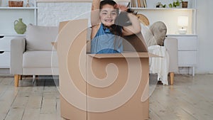 Happy Caucasian child girl jump out of cardboard box surprise delivery present with daughter inside play game hide and