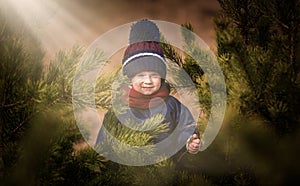 Happy caucasian child playing outdoor - hiding behind pine tree
