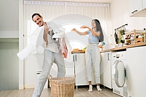 Happy Caucasian couple having fun doing laundry together. Couples stand and throw clothes with fun and laugh together.