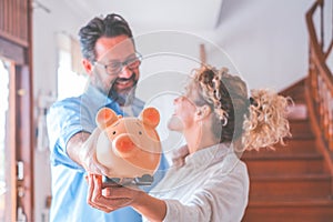 Happy caucasian couple holding piggy bank to save money to make their future dreams come true. Husband and wife holding piggy bank