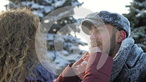 Happy Caucasian couple hugs and laughs outdoors in winter. A romantic couple is having a good time in a snowy city park