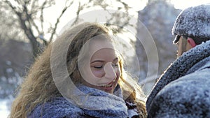 Happy Caucasian couple hugs and laughs outdoors in winter. A romantic couple is having a good time in a snowy city park