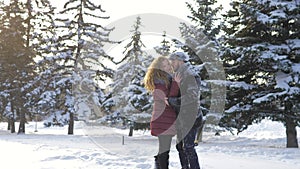 Happy Caucasian couple hugs and laughs outdoors in winter. A romantic couple is having a good time in a snowy city park