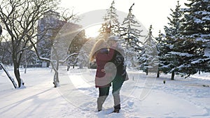 Happy Caucasian couple hugs and laughs outdoors in winter. A romantic couple is having a good time in a snowy city park