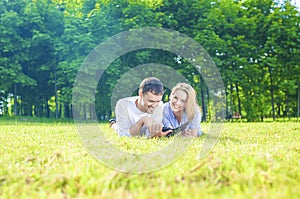 Happy Caucasian Couple in Love Lying on the Grass Outdoors. Read